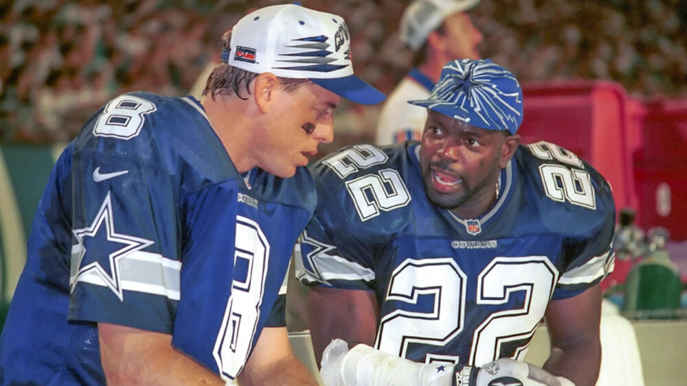 Dallas Cowboys Troy Aikman and Emmitt Smith talk while seated on the sidelines of a game against the Miami Dolphins at Pro Player Stadium in Miami, Fla.